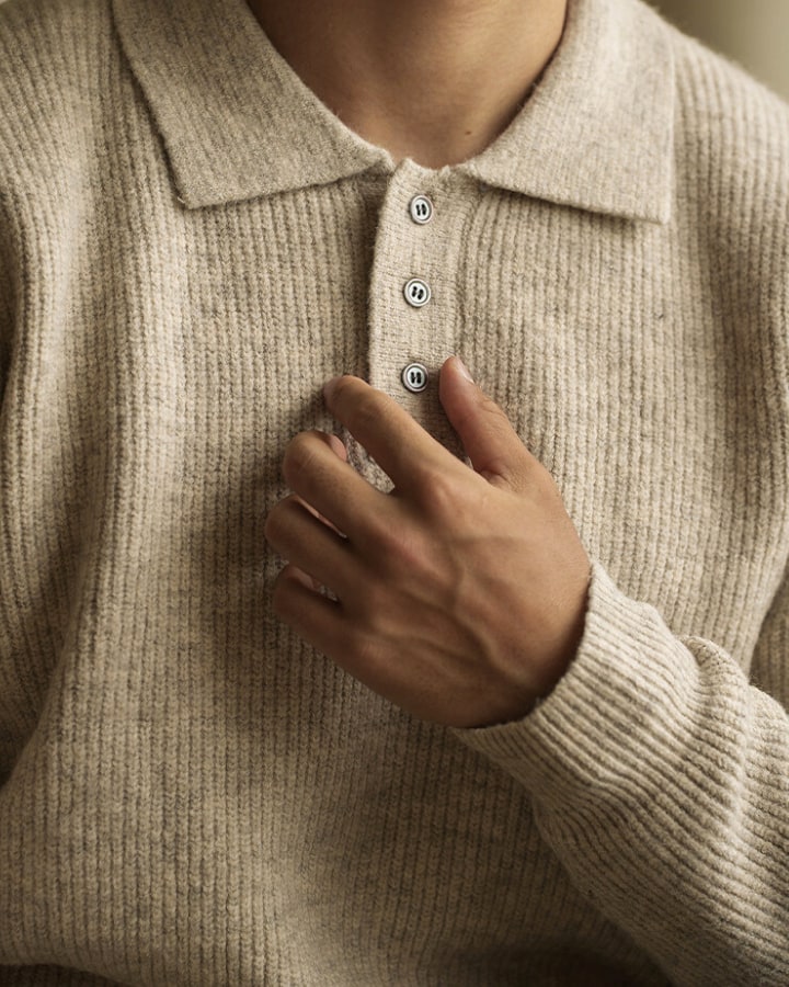 Nærbillede af krave og knapper på beige polosweater