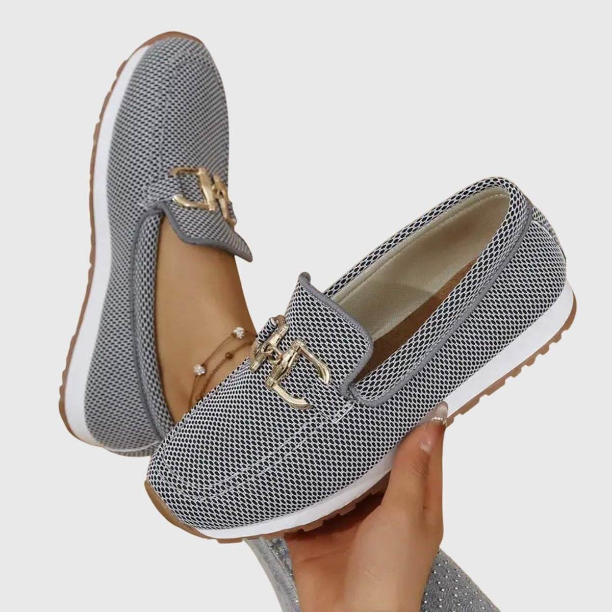Grå loafers i åndbar strik holdt i hånden, der viser den lette sål 7